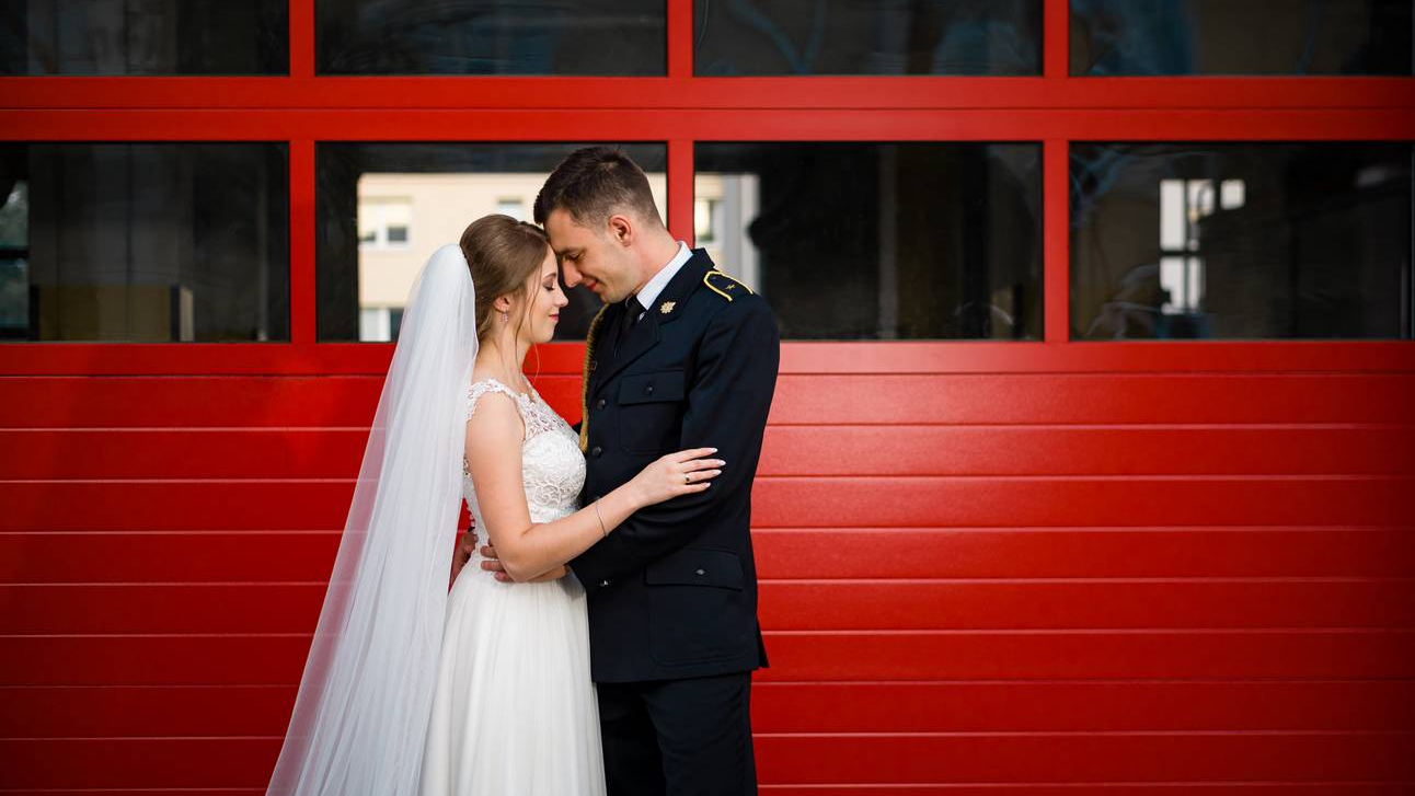 Sesja ślubna w Straży Pożarnej w Lublinie Para Młoda na tle czerwonych drzwi straży pożarnej