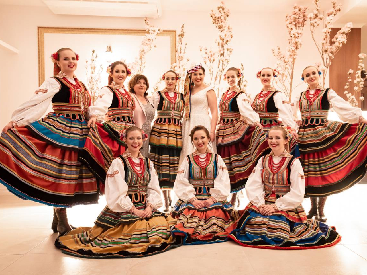 Zdjęcie grupowe na którym jest Panna Młoda i ubrane na ludowo koleżanki z zespołu ludowego 