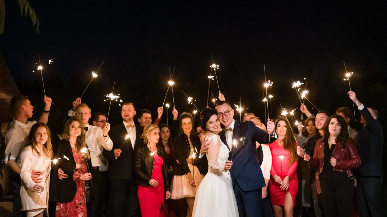 Sesja z zimnymi ogniami Para Młoda z gośćmi trzymają zapalone zimne ognie